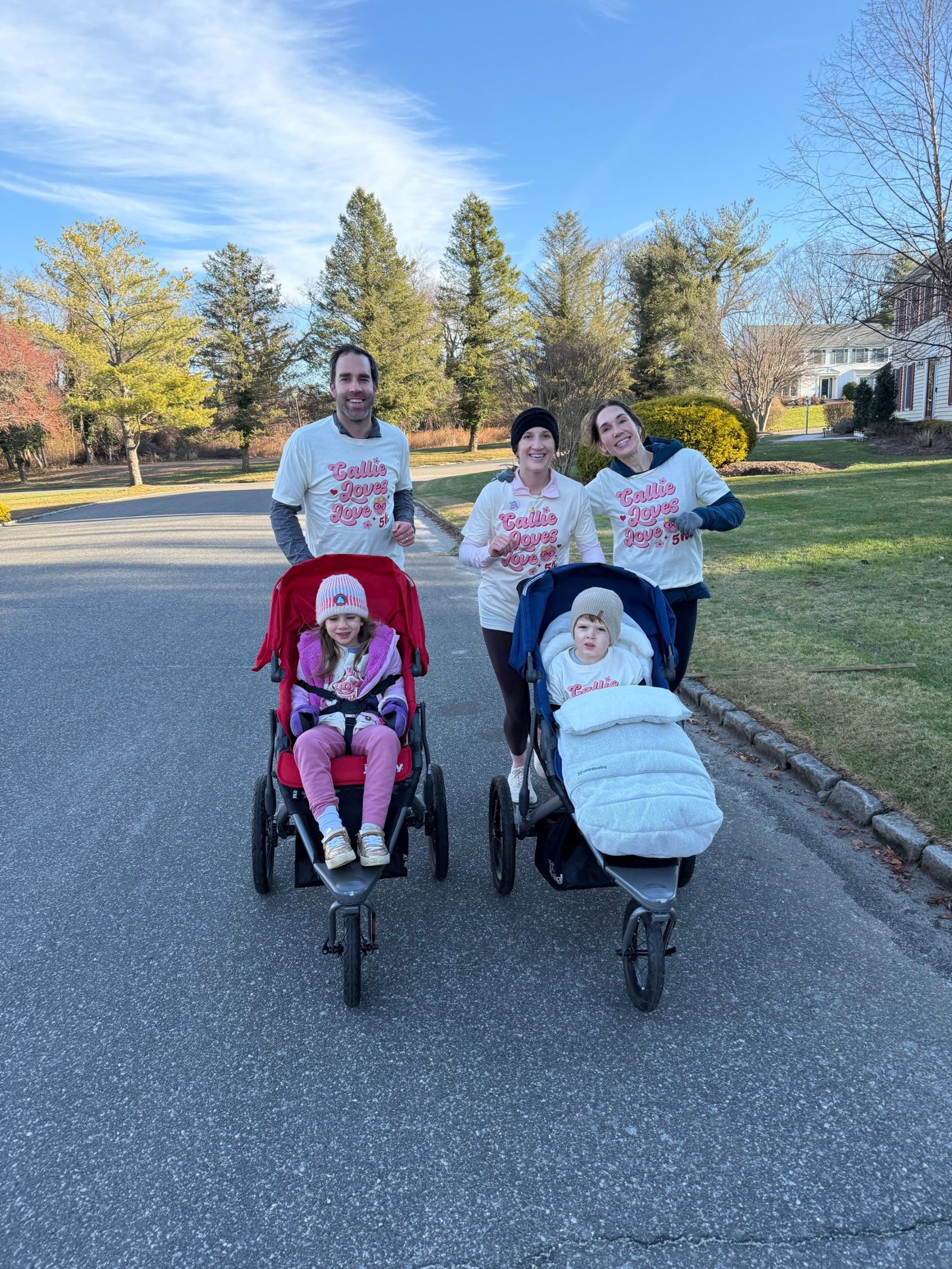 Runners in Callie Loves Love shirts pushing two jogging strollers